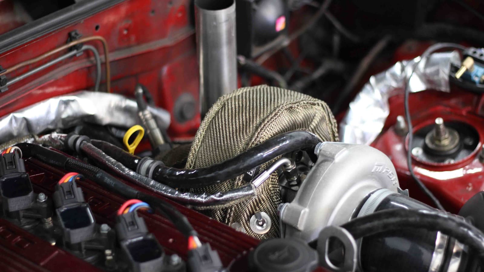 Heat-discolored plastic and new wiring sleeve in a repaired engine bay